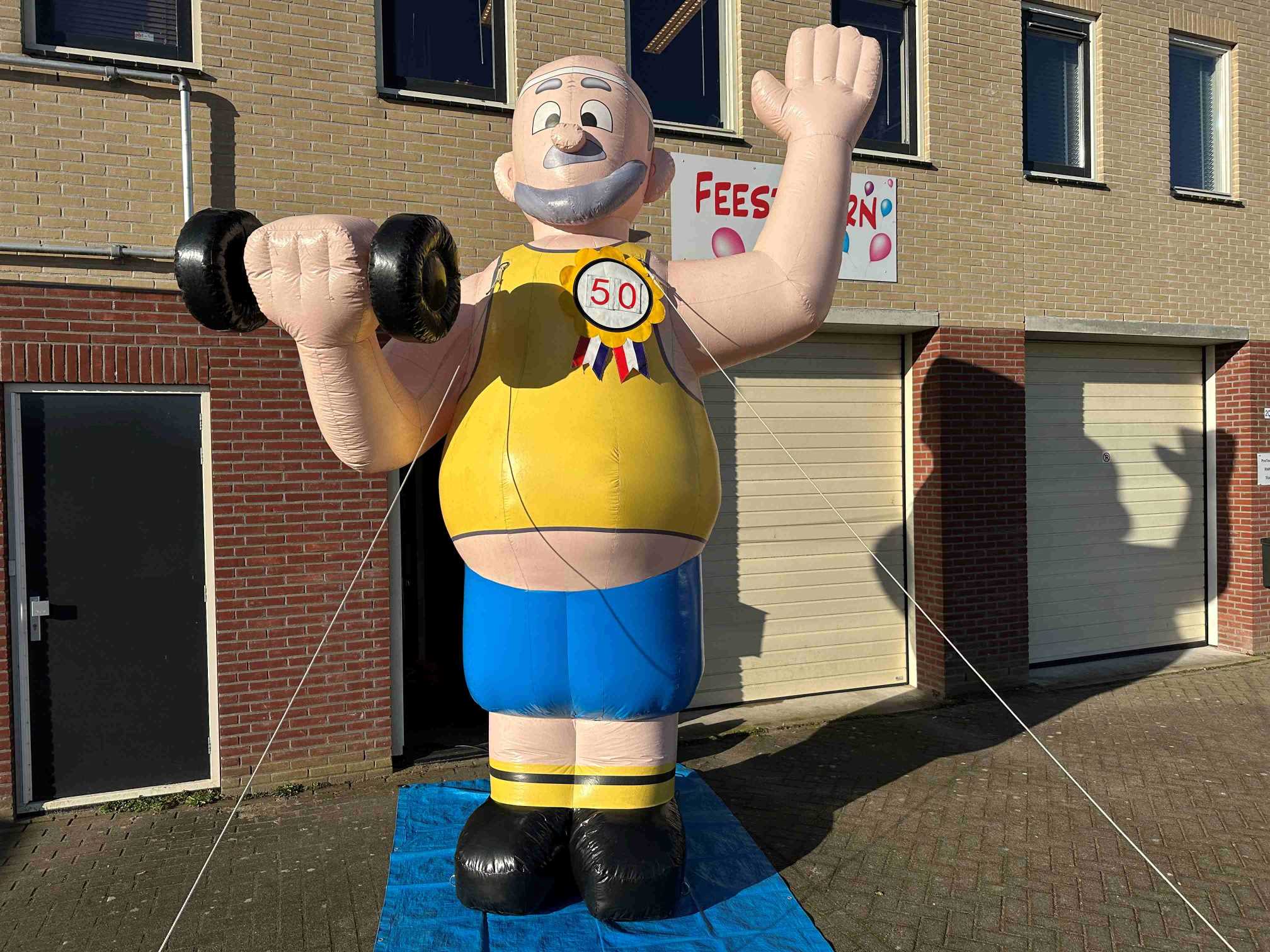 De Abraham XL Sport pop, met een dumbell in de hand, voor de sportieve jarige. Deze pop is geschikt voor alle verjaardagen, de leeftijd-rozet kan namelijk aan iedere leeftijd worden aangepast.