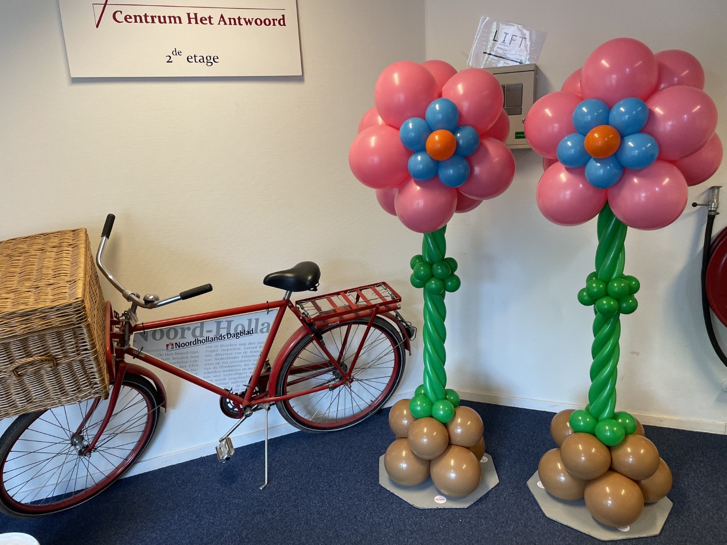 Bloempilaren met ballonbloemen in de top en modeleerballonnen als steel in de stam en een cluster ballonnen op de grond.