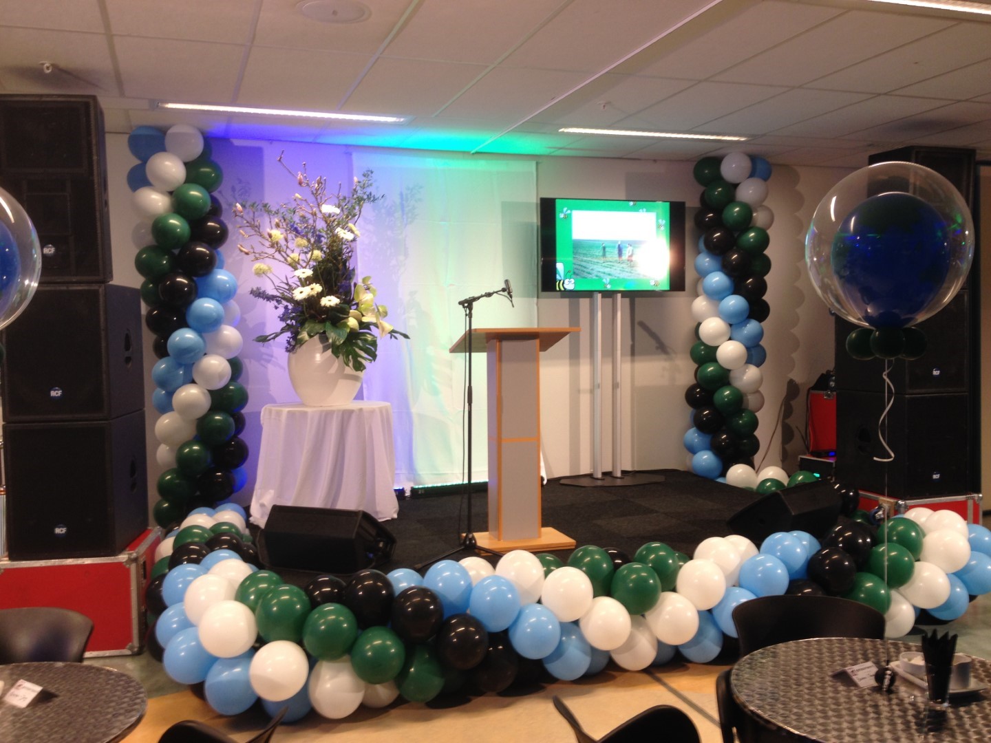 Podiumdecoratie. Ballonnenslingers rondom het podium gemonteerd.