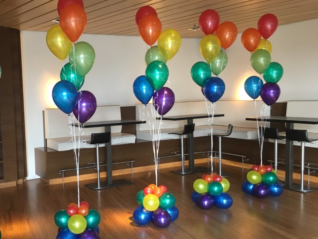 Langdrijvend heliumgevuld in de regenboog kleuren samengesteld aan lint voorzien van een verzwaard grondcluster van ballonnen.