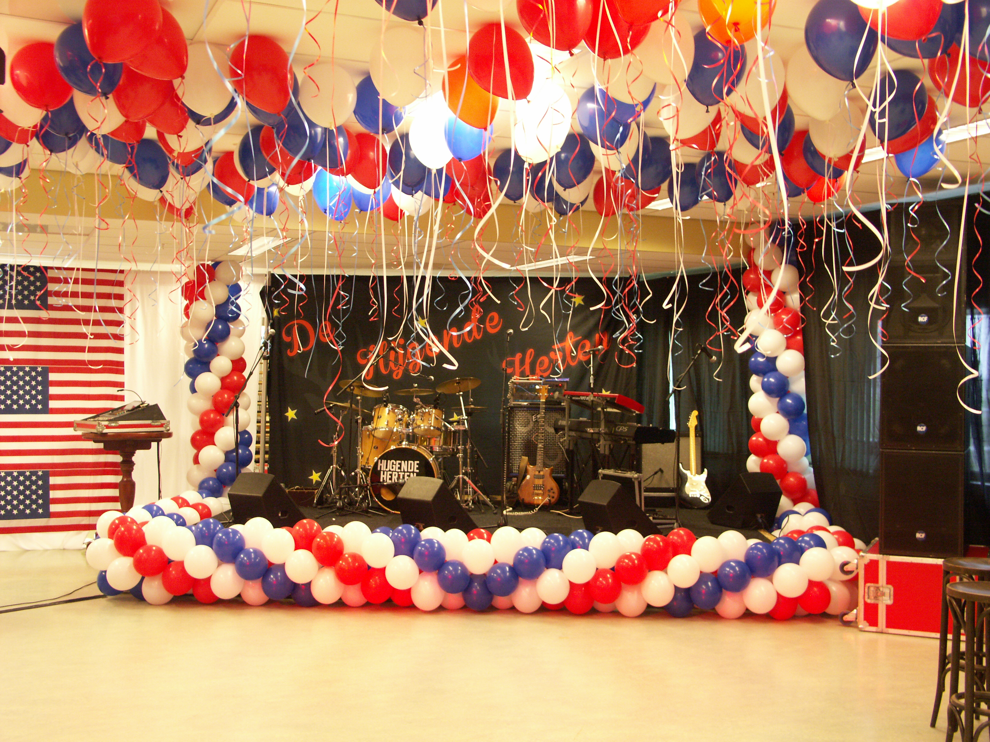 Podium aangekleed met ballonnen en losse heliumballonnen tegen het plafond